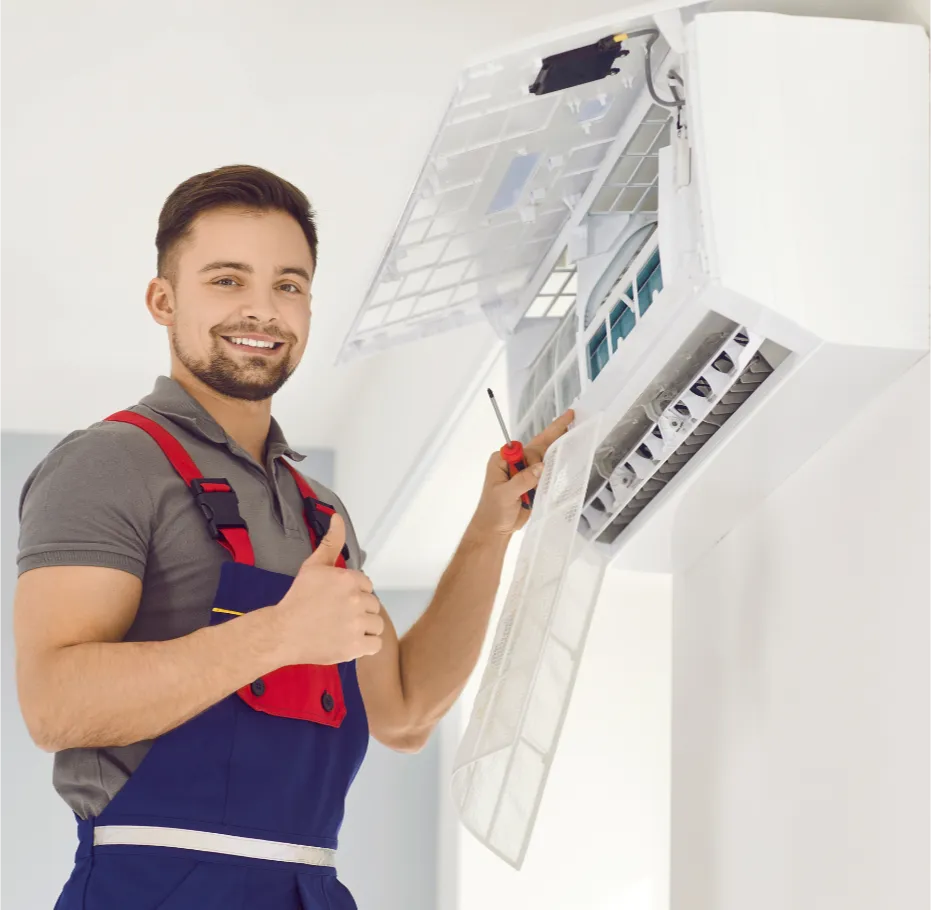 ac-install-3 Smiling technician in uniform repairs air conditioner, holding a screwdriver and giving a thumbs up.
