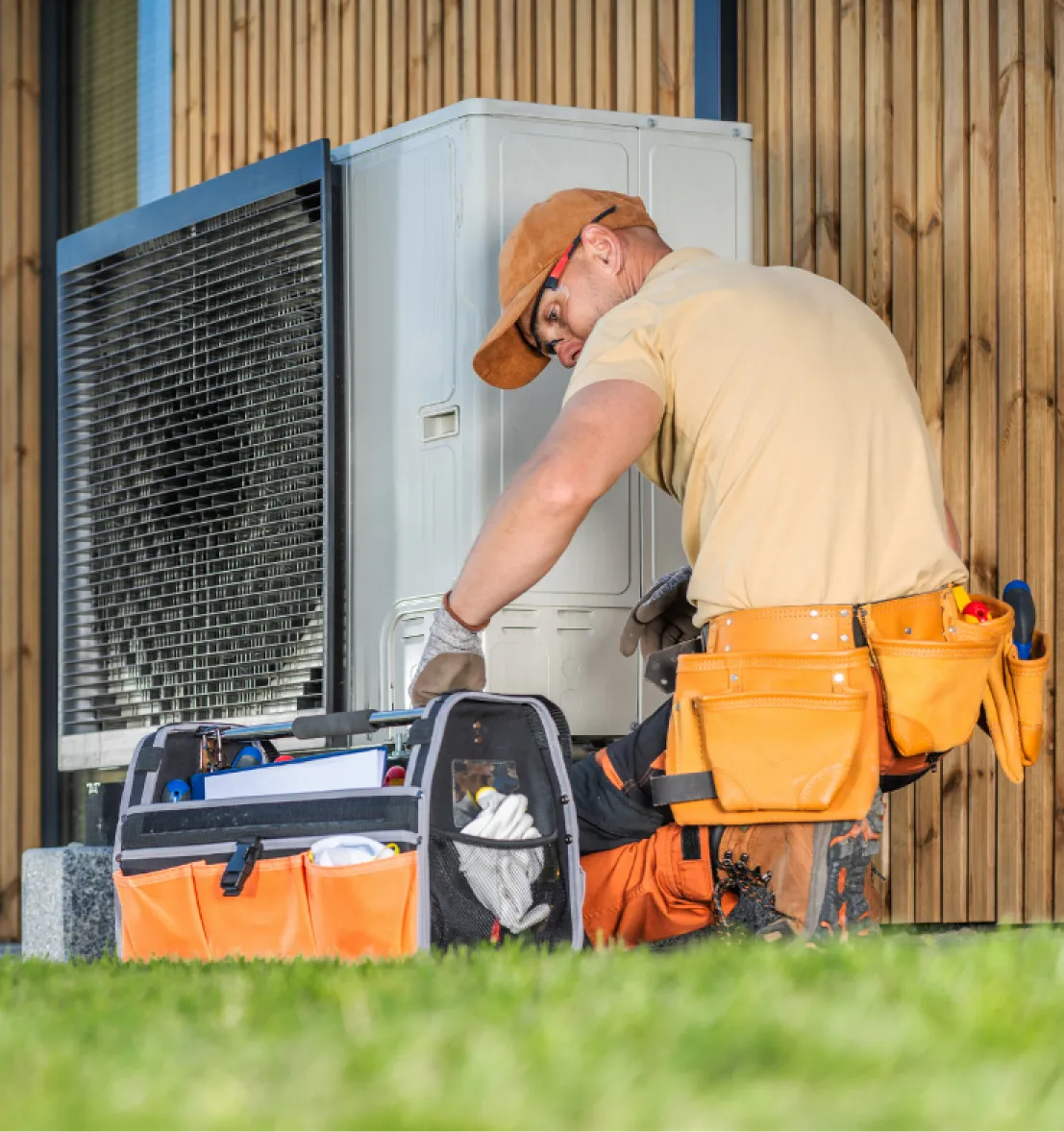 heating-repair-1 Technician repairing an outdoor HVAC unit with tools and equipment, working next to a building.