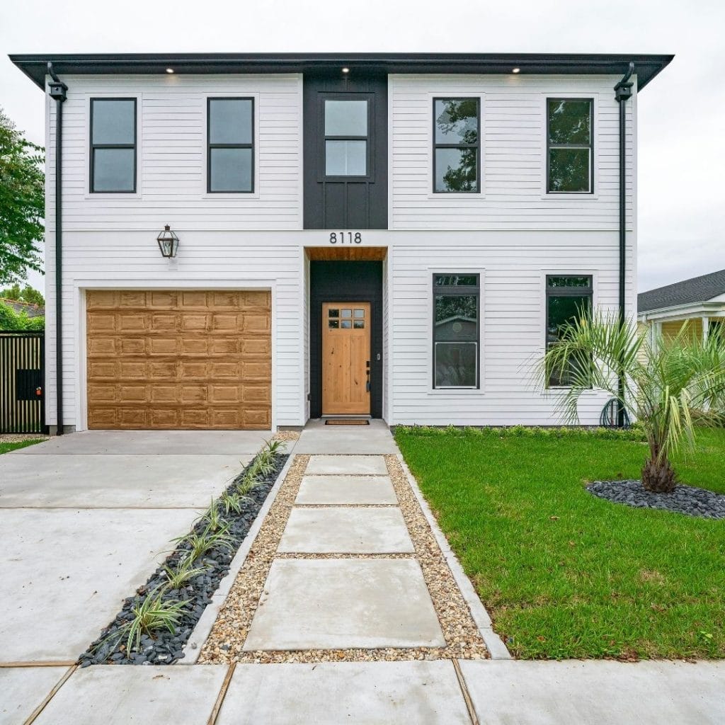 Modern two-story white house with wood accents, a single garage, and a landscaped front yard.